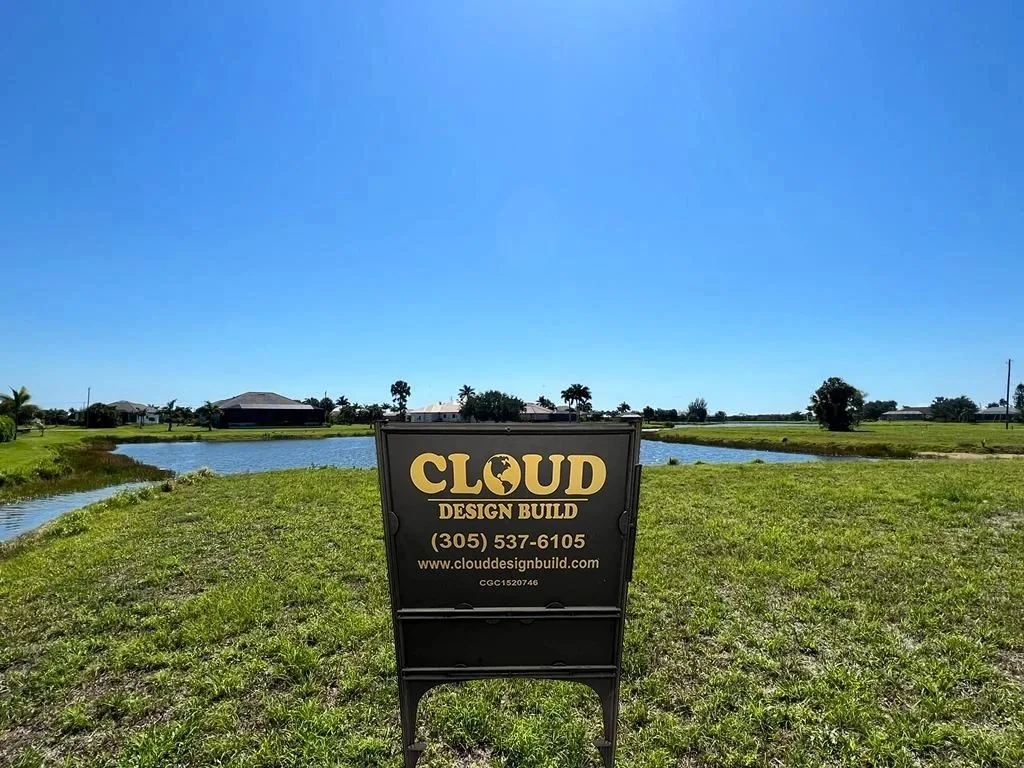 Cloud Design Build yard sign with contact info beside a neighborhood pond