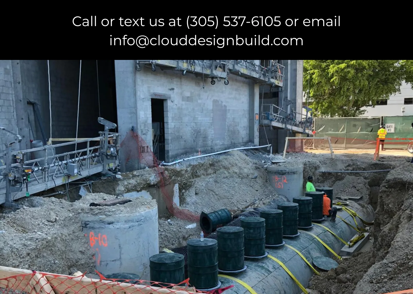 Large concrete culvert sections being installed in a trench next to an existing building