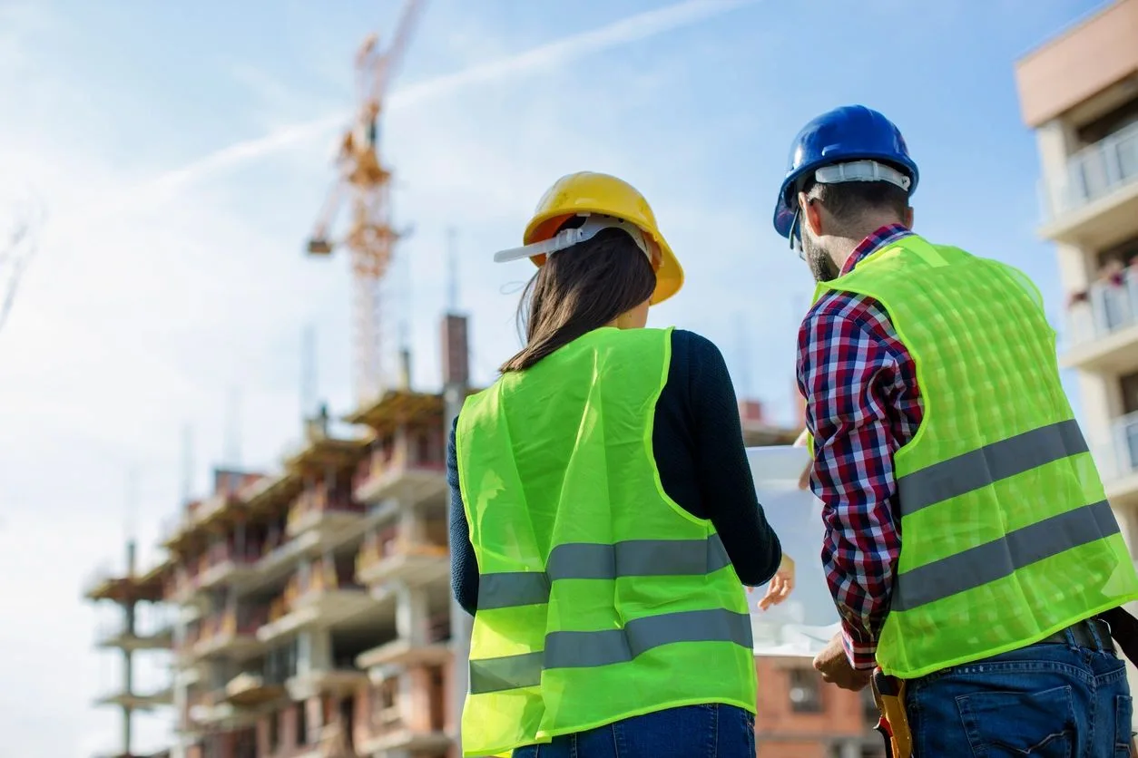 Two consultants in safety vests viewing a high-rise construction site