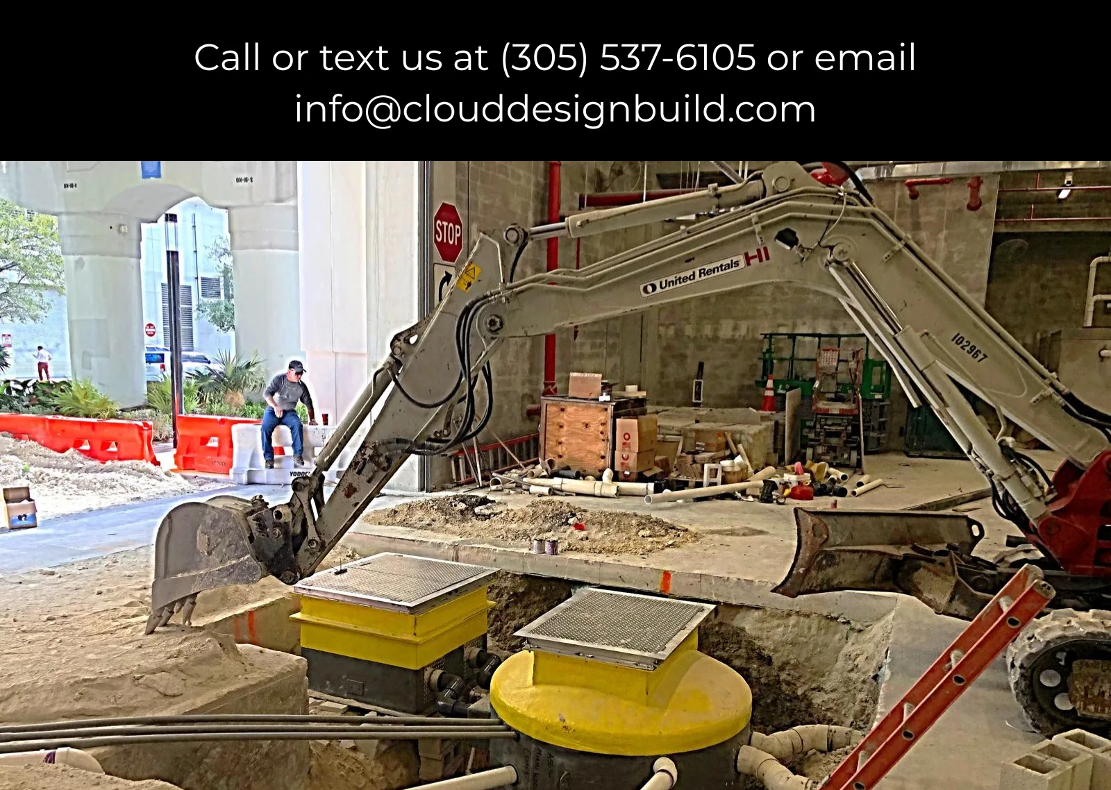 Excavator working near underground utility access covers at an urban construction site