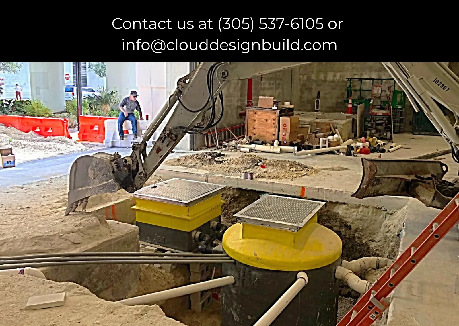 Excavator digging around utility vaults at a high-rise construction site in Surfside