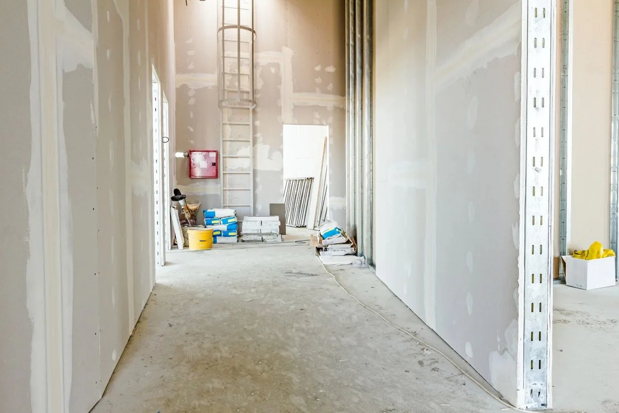 Hallway with newly taped drywall walls and building materials staged on the floor
