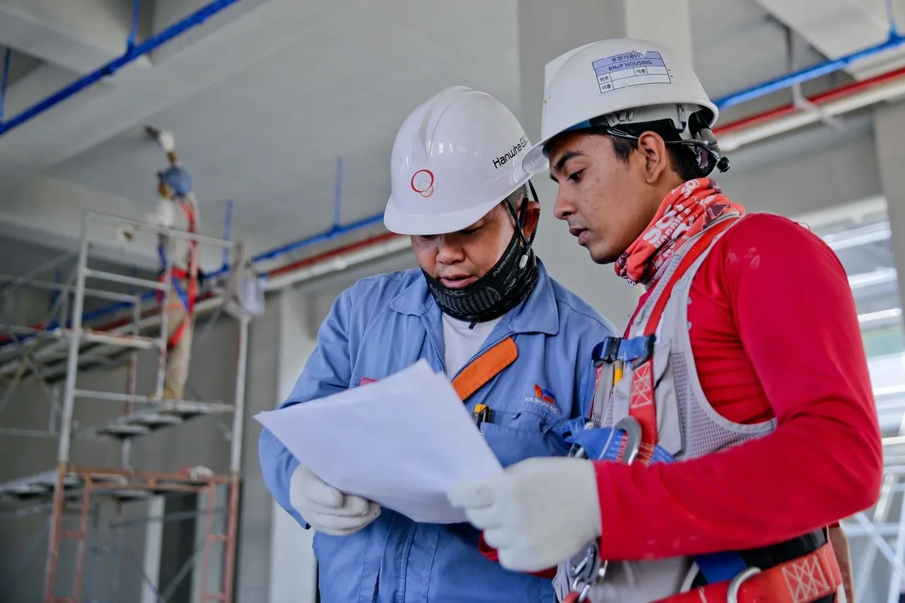 Two inspectors reviewing documents inside a building under construction