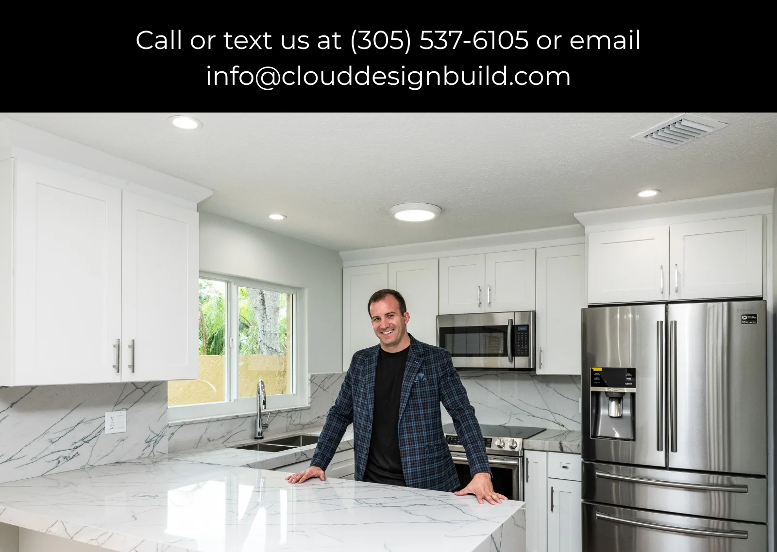 James J. Cloud, general contractor, standing in a renovated white kitchen with a marble island