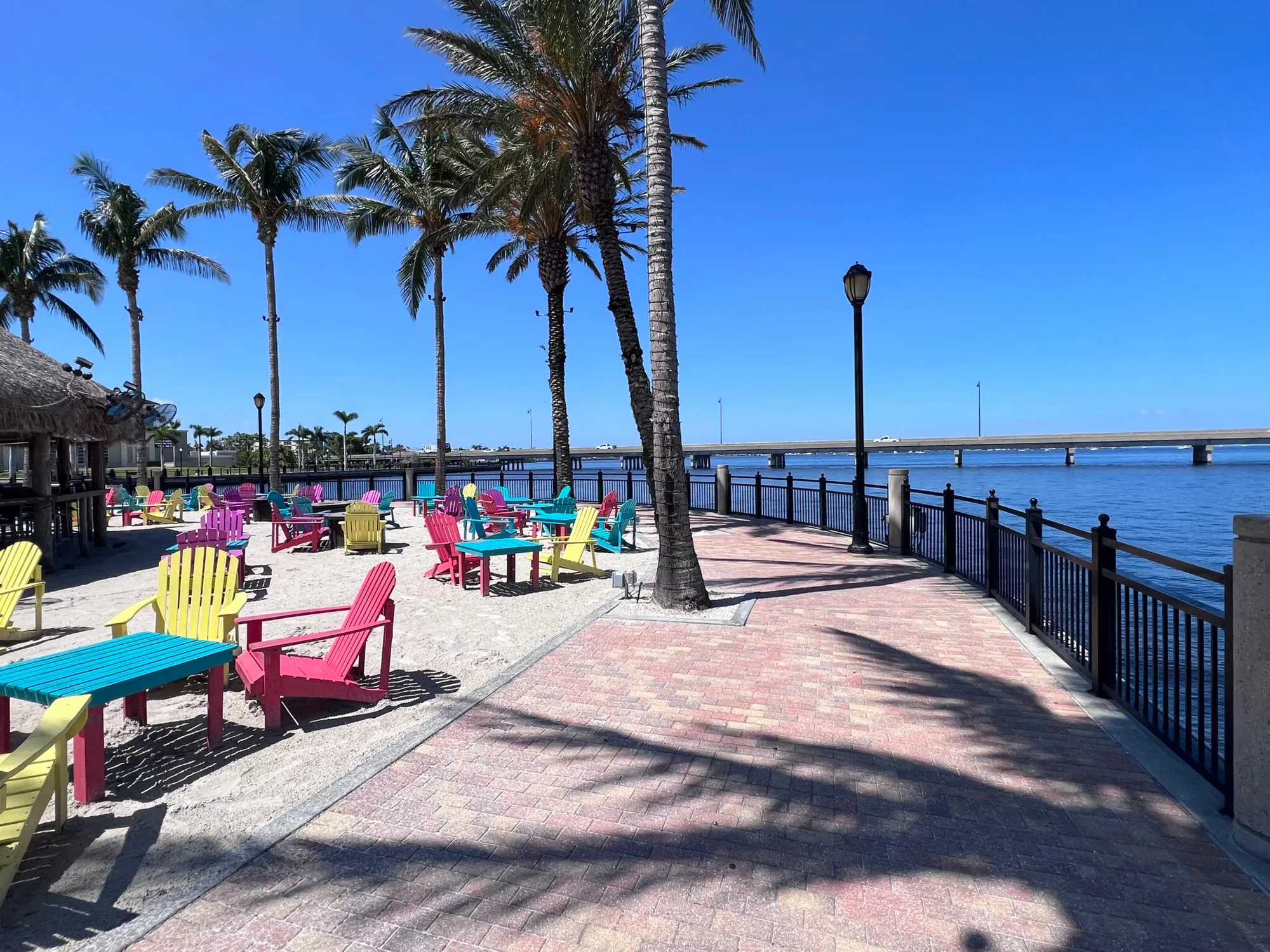 Waterfront boardwalk in Punta Gorda with colorful painted chairs, palm trees, and a bay view