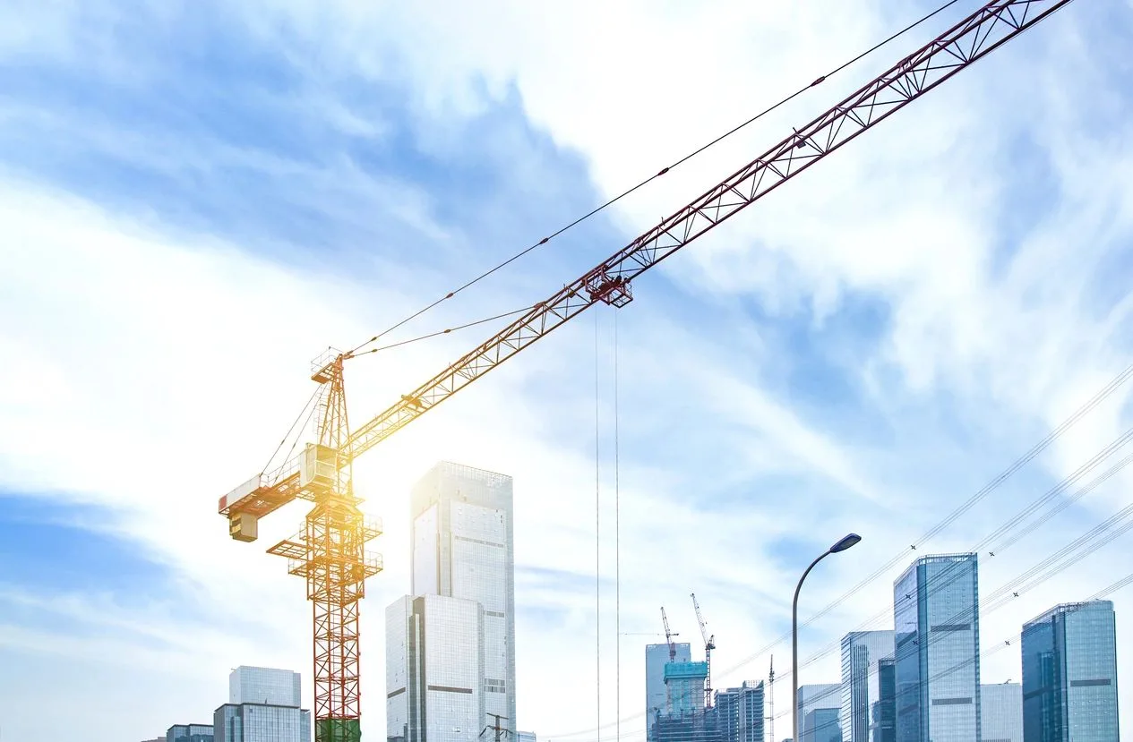 Tower crane rising above a city skyline at a commercial construction site