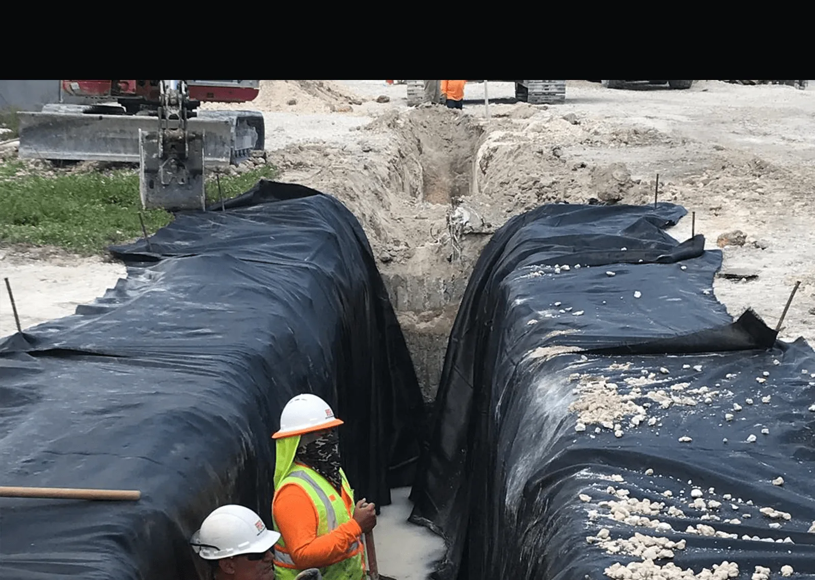 Trench lined with geotextile fabric and gravel during utility construction