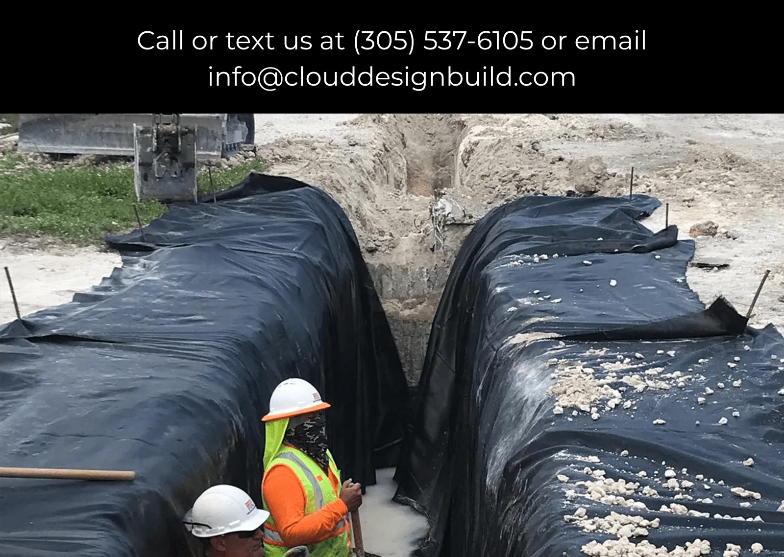 Construction workers inspecting a trench lined with black geotextile fabric at a job site