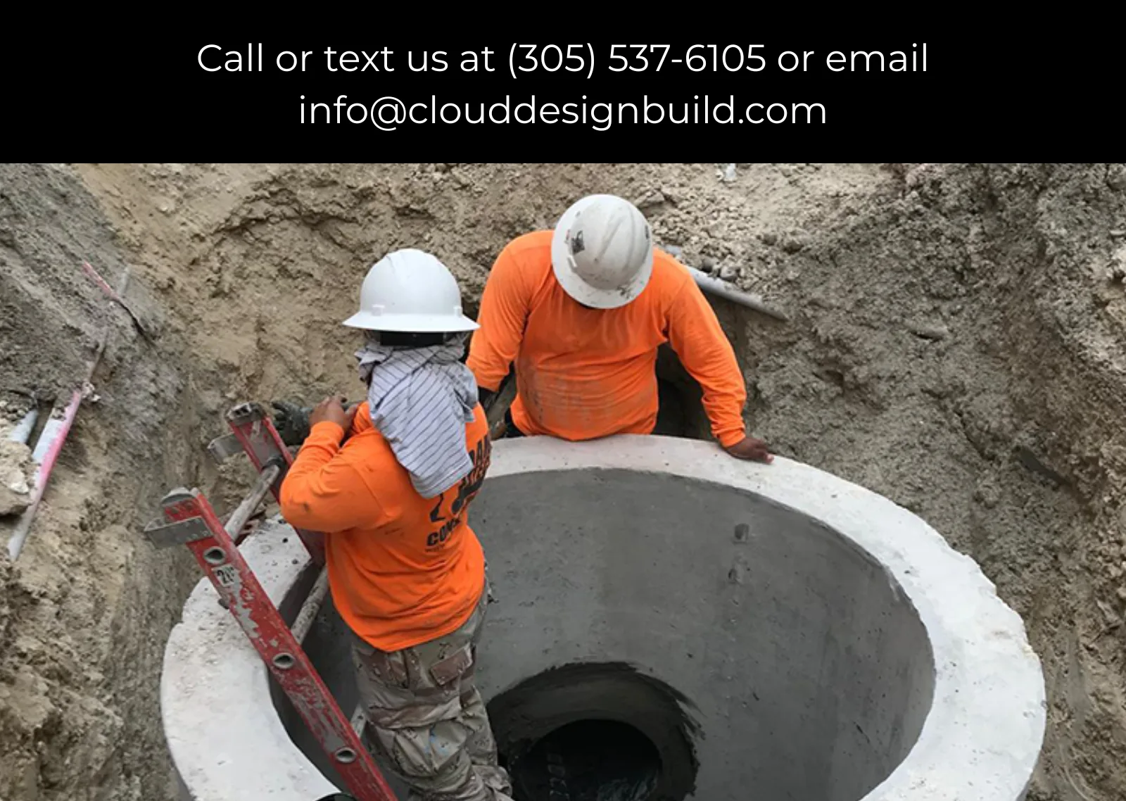 Two workers in hard hats standing inside a large concrete utility vault