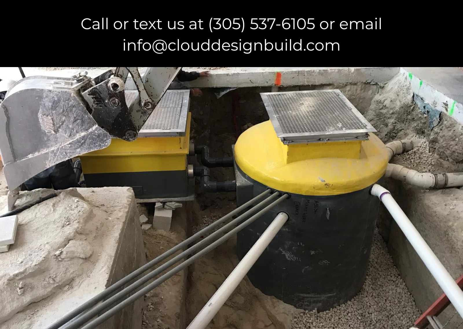 Underground utility vault with yellow access covers and connecting pipes at a construction site