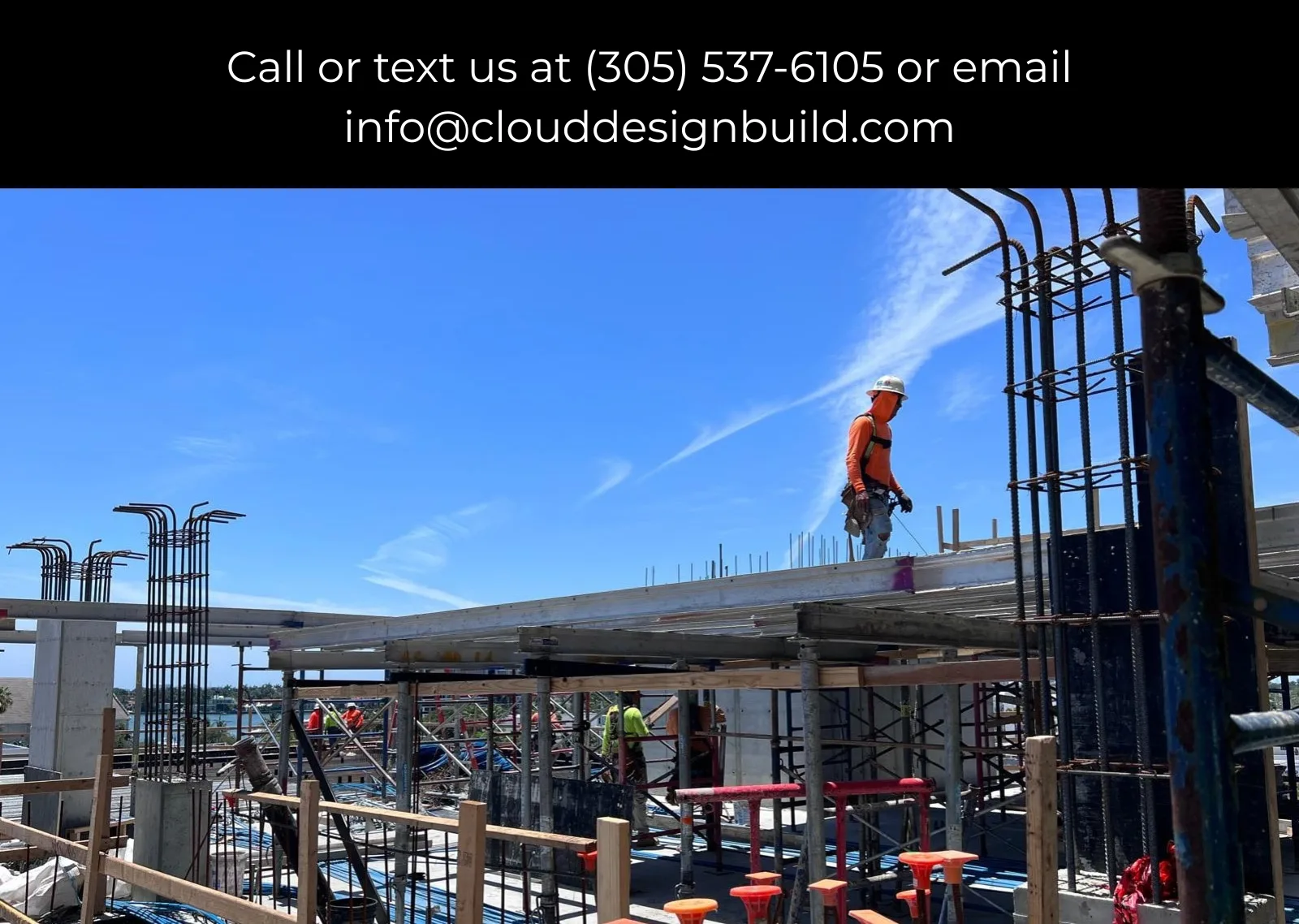 Worker in a hard hat and safety harness on an elevated concrete deck at a high-rise construction site
