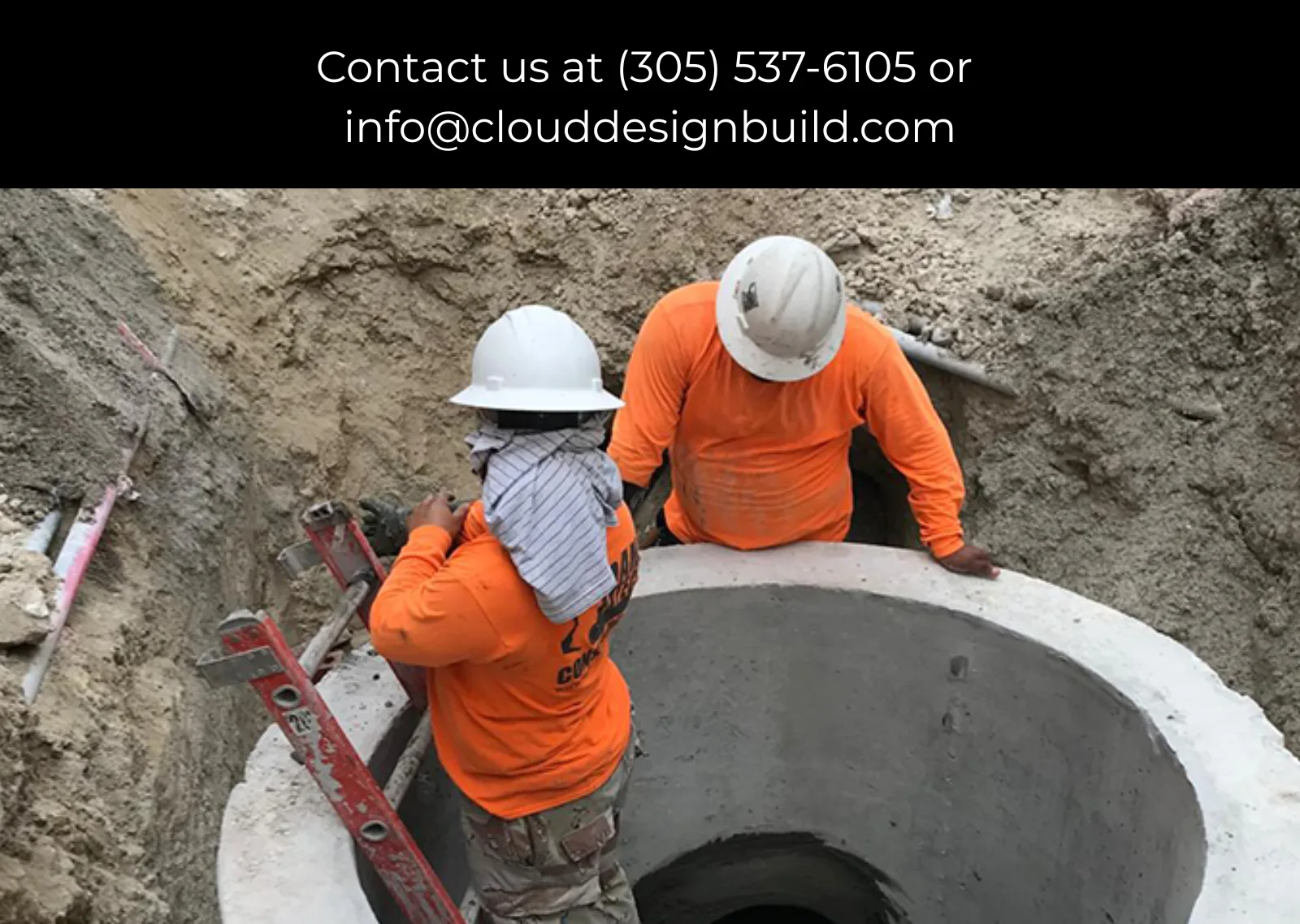 Workers in hard hats lowering equipment into a concrete utility vault