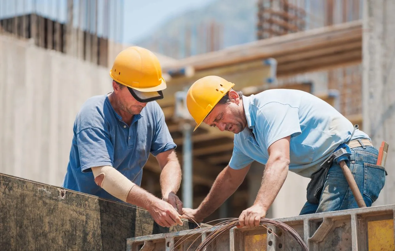 Two construction workers tying rebar reinforcement at a job site